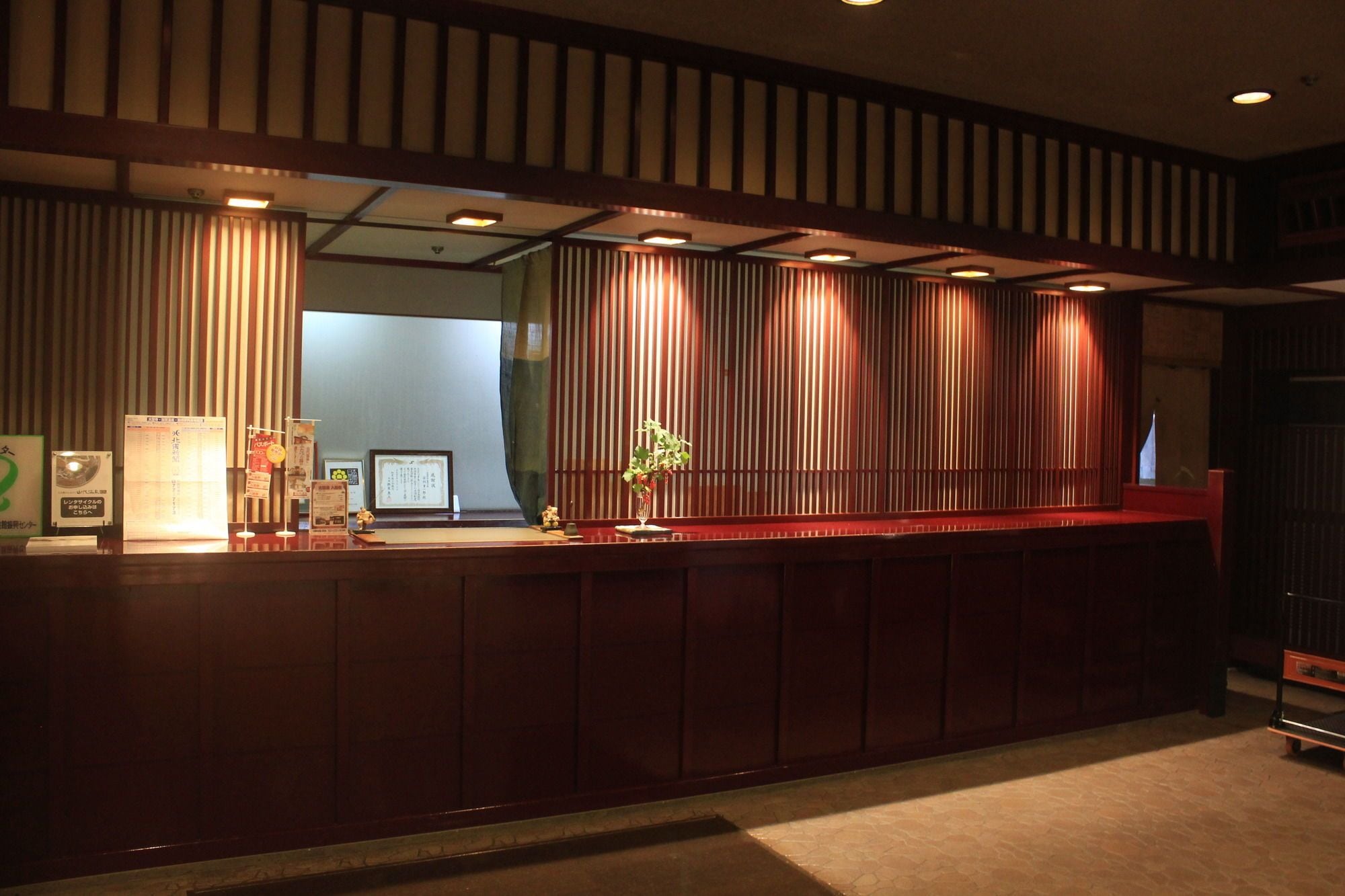 A reception desk with a dark wood finish, a glass partition, and a small potted plant.
