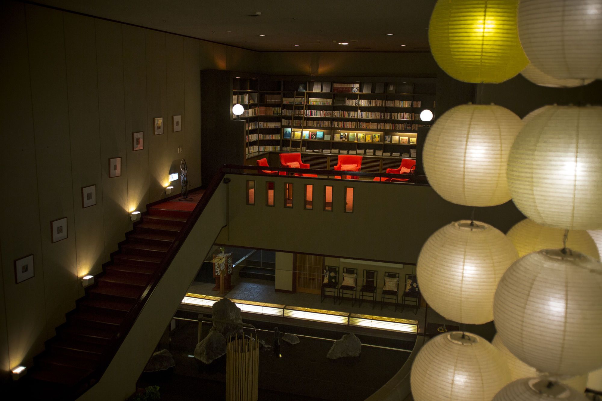 A multi-level interior with a staircase, bookshelves, and a seating area.