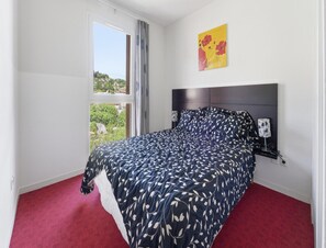 A bedroom with a bed, a window with curtains, a nightstand with a lamp, and a painting on the wall. - Sunlit Holiday Apartment in Grasse for 4 (Grasse)