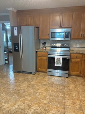 A kitchen with a refrigerator, microwave, oven, and wooden cabinets. - Queen Anne's Retreat-Southern charm and comfort ! (Harvest)