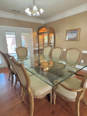 A dining area with a glass-top table surrounded by ornate chairs, a chandelier, and a framed picture on the wall. - Queen Anne's Retreat-Southern charm and comfort ! (Harvest)