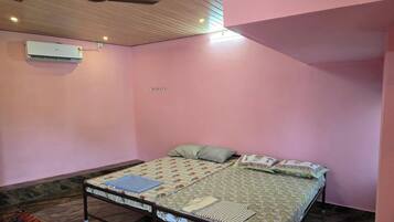 Un dormitorio con cama, almohadas, manta, techo de madera y aire acondicionado.