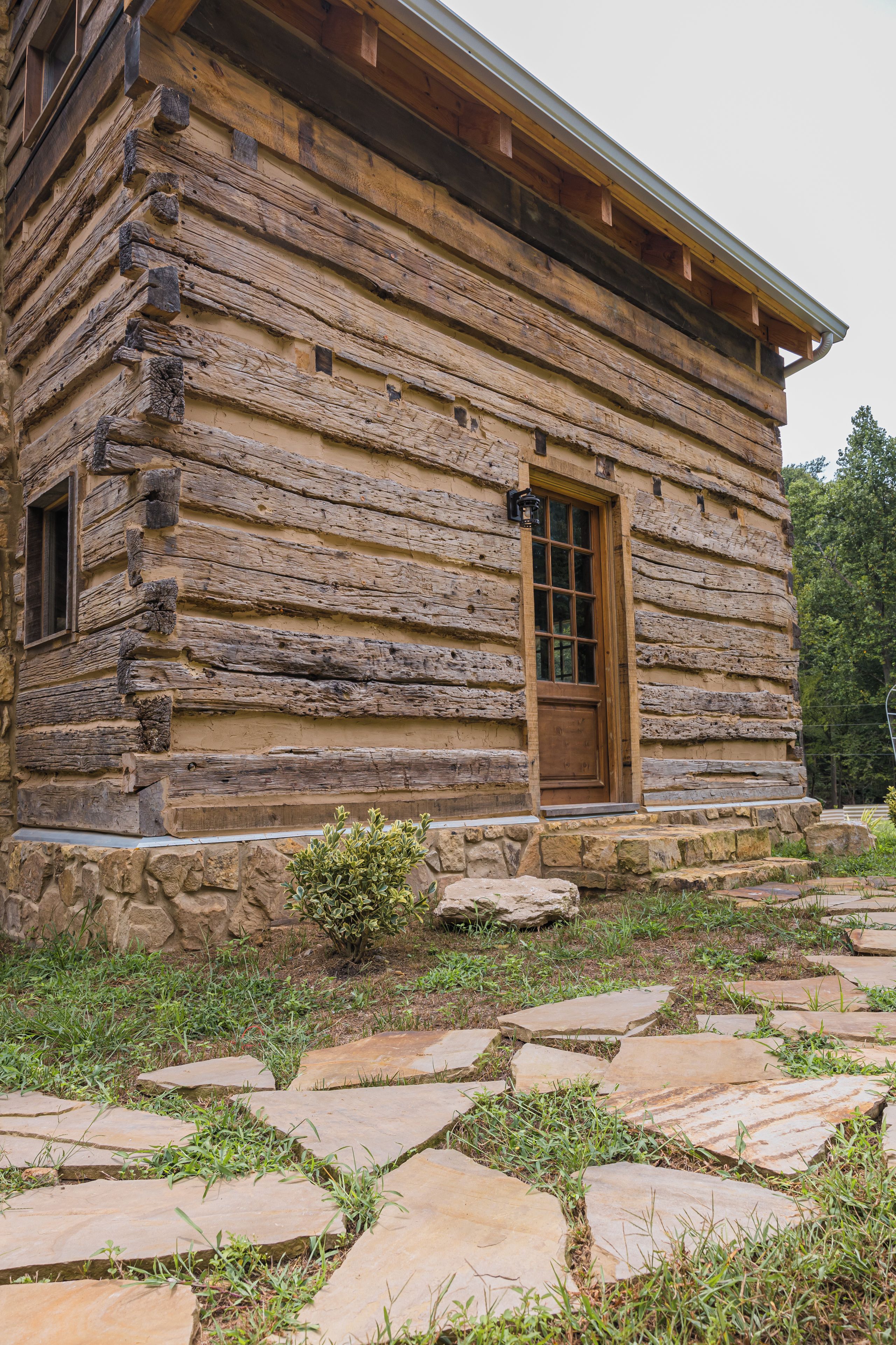 A log cabin with a stone foundation and a wooden door.