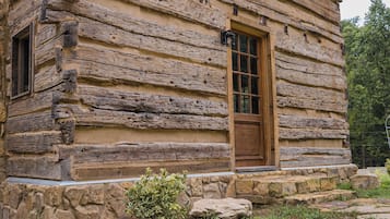 A log cabin with a stone foundation and a wooden door.