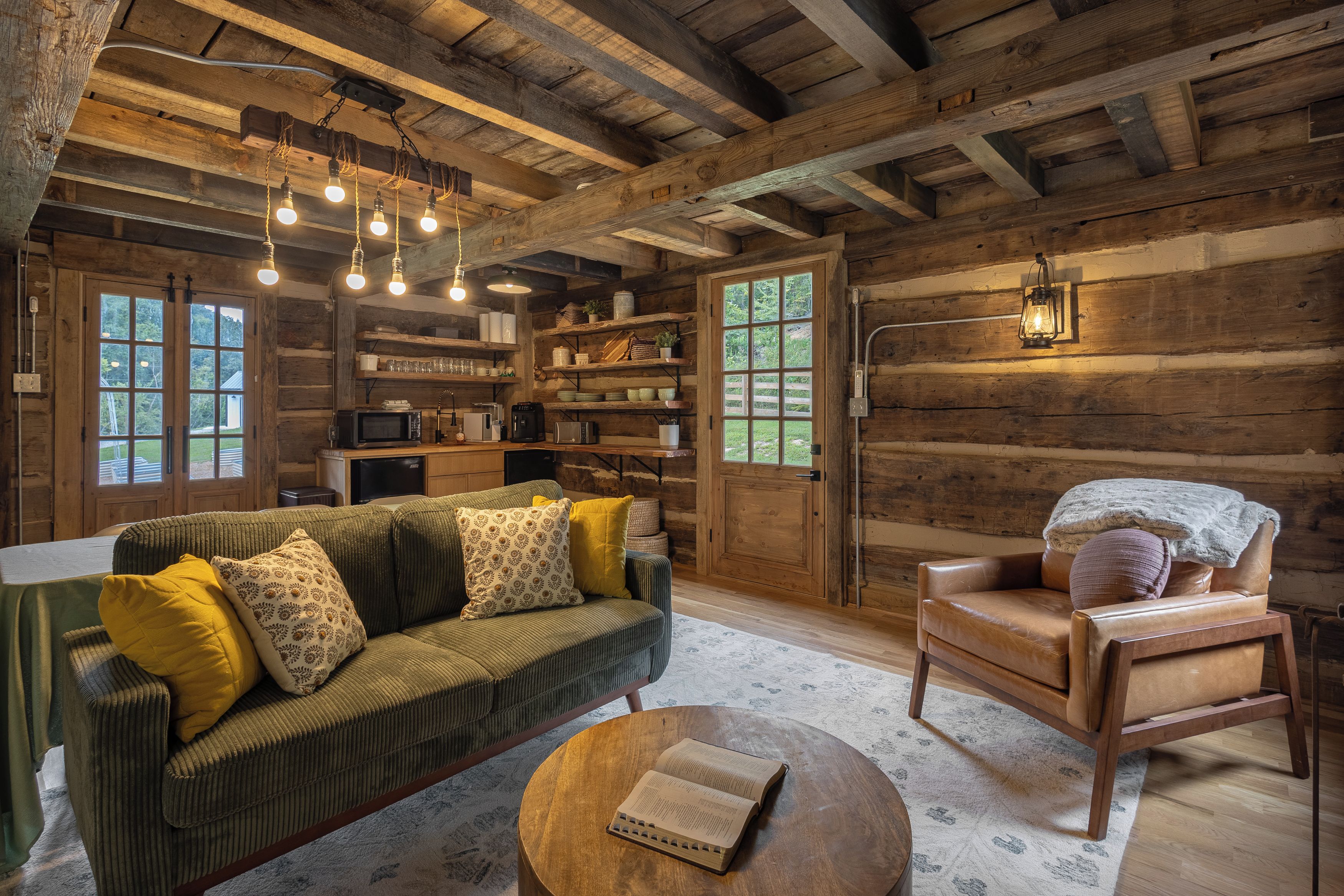 A rustic cabin interior with a sofa, armchair, and round coffee table.
