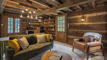 A rustic cabin interior with a sofa, armchair, and round coffee table.