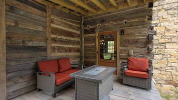 A log cabin with a stone wall, a wooden ceiling, and a glass door.