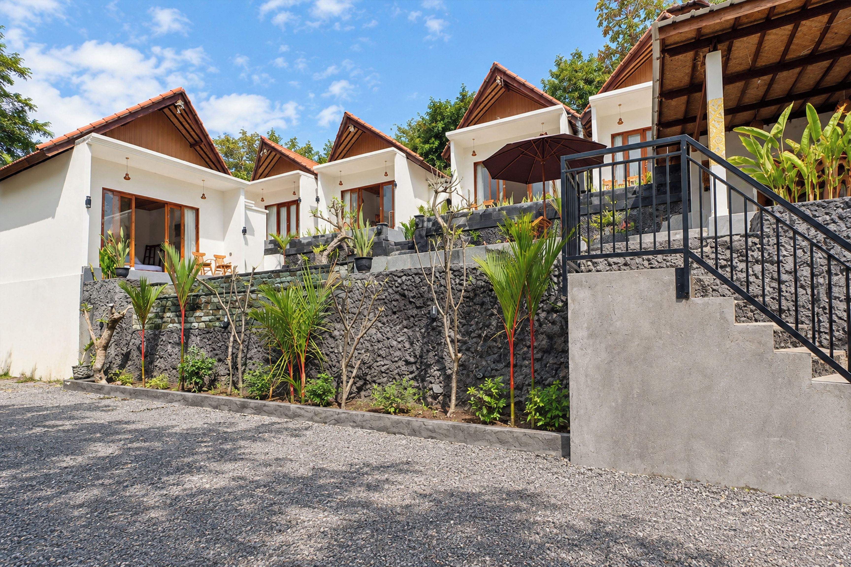 Un hilero de villas modernas con un muro de contención de piedra y plantas tropicales.