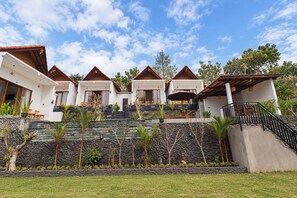 Un resort con diversi edifici in stile bungalow, un muro di sostegno in pietra e un prato.