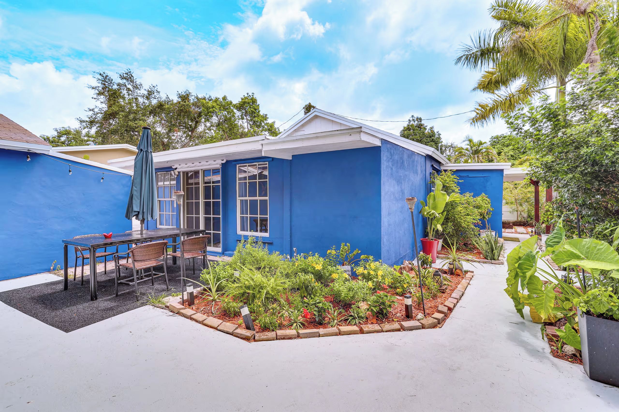 Una casa azul con un patio, mobiliario exterior y un jardín.