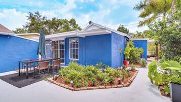 Una casa azul con un patio, mobiliario exterior y un jardín.