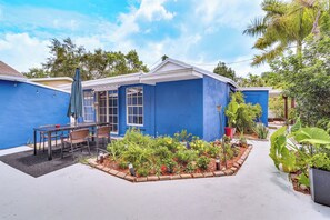 Una casa azul con un patio, mobiliario exterior y un jardín.