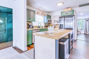 A modern kitchen with green cabinets, stainless steel appliances, and a central island.