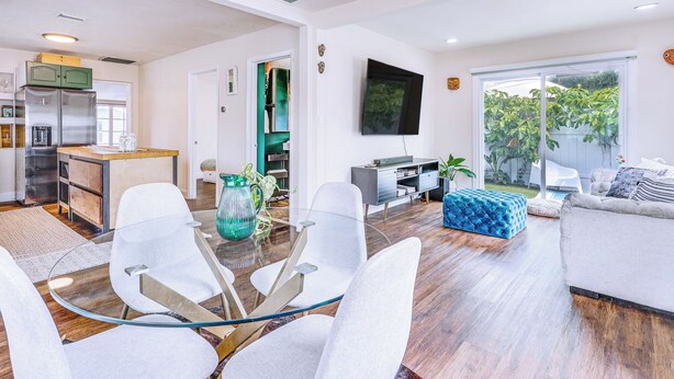 A modern living room with a glass coffee table, white chairs, a blue ottoman, and a grey sofa. - Miami Garden Retreat, Sleeps 8, Near Beaches (North Miami Beach)