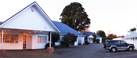 A single-story building with a pitched roof, a covered porch, and a car parked in front.