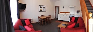 A compact living space with a dining area, kitchenette, and a red sofa. - Asure Colonial Court Motel and Conference Centre (Palmerston North)