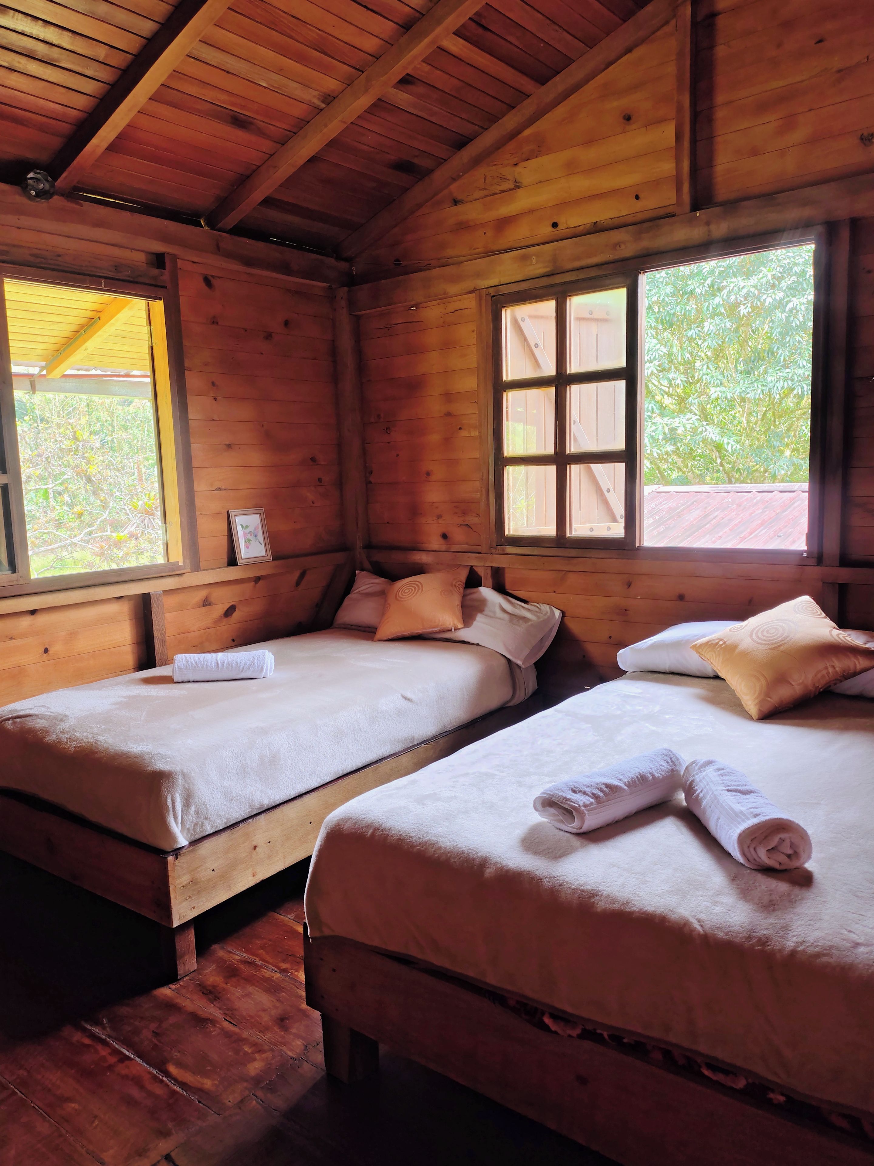 Une chambre dans un chalet en bois, avec deux lits, chacun équipé d’un oreiller et d’une serviette enroulée.