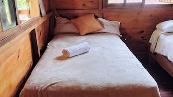 Una habitación tipo cabaña de madera con una cama individual, una ventana y una puerta.