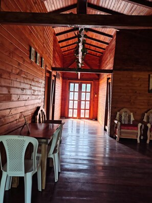 Interior de una cabaña de madera con una mesa de comedor, sillas y un banco.