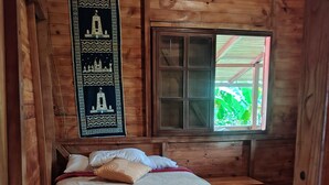Een houten kamer met een bed, een raam en een decoratie aan de wand.