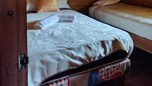 Een houten kamer met twee bedden, een houten plafond en een deur.