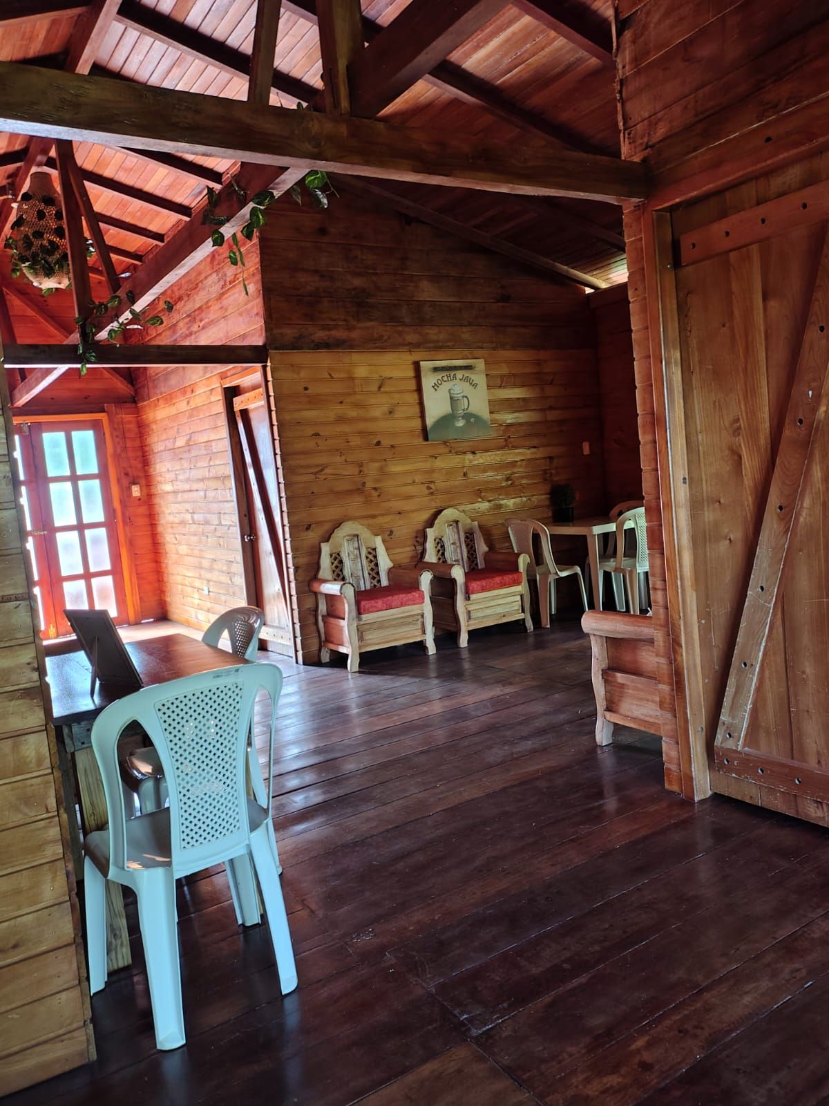 A rustic wooden interior with a dining area, wooden benches, and a table.