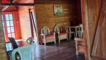 A rustic wooden interior with a dining area, wooden benches, and a table.