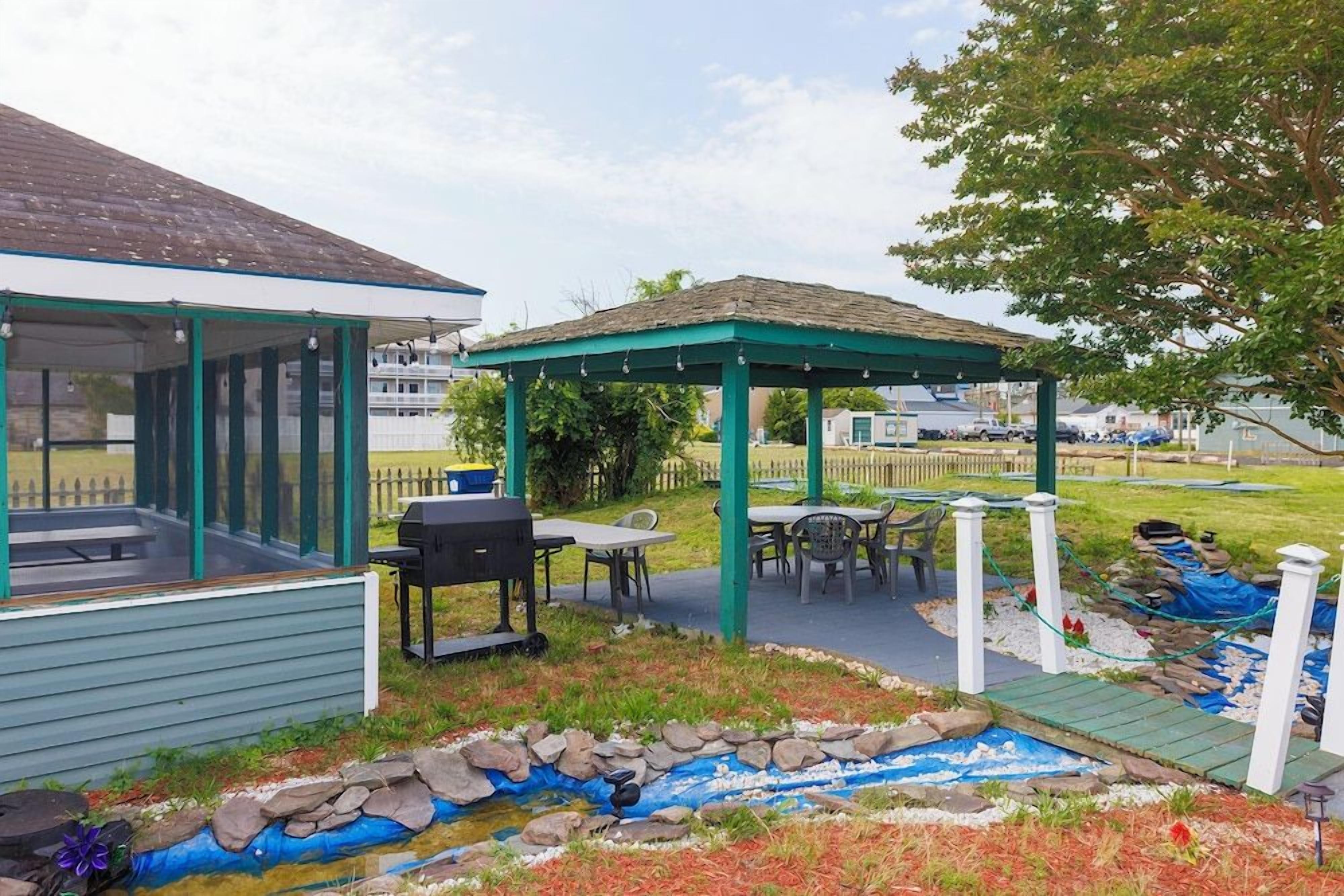A covered outdoor area with a barbecue grill, tables, and a small garden feature.