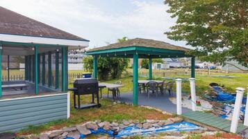 A covered outdoor area with a barbecue grill, tables, and a small garden feature.