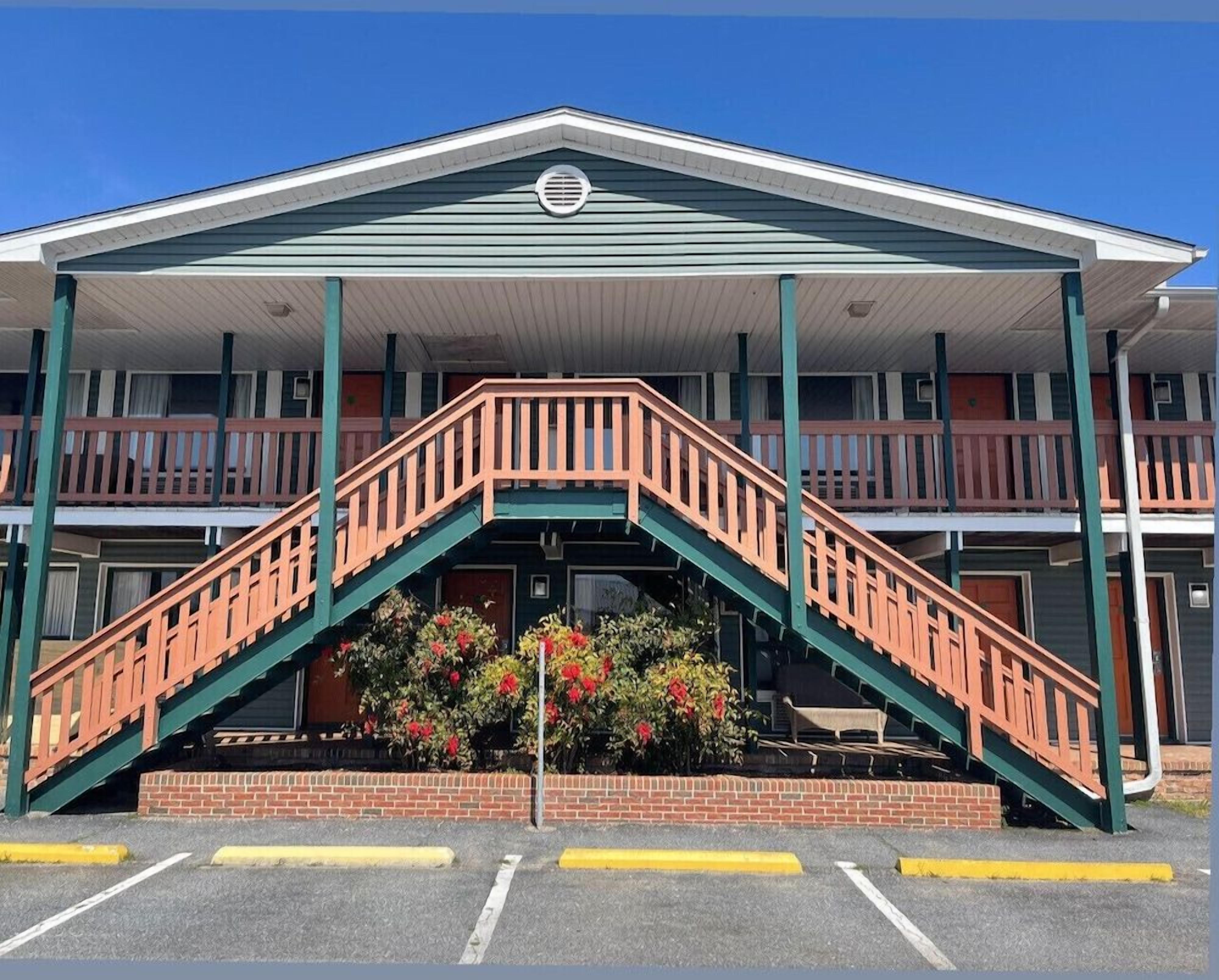 A two-story motel with a central staircase and a covered front porch.