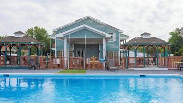 A swimming pool area with a building and two gazebos.