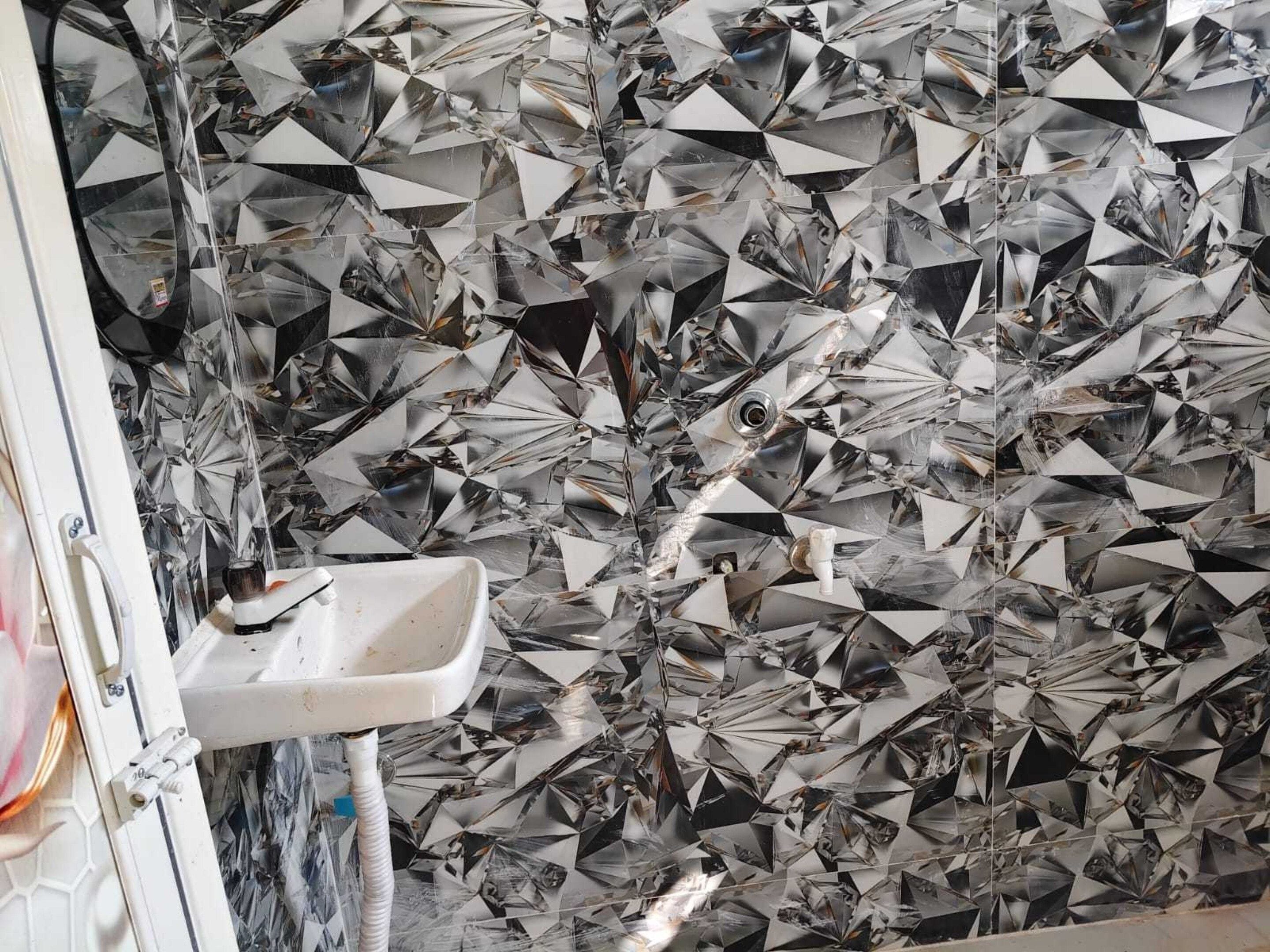 Un baño con un lavamanos y una pared revestida de baldosas geométricas reflectantes.