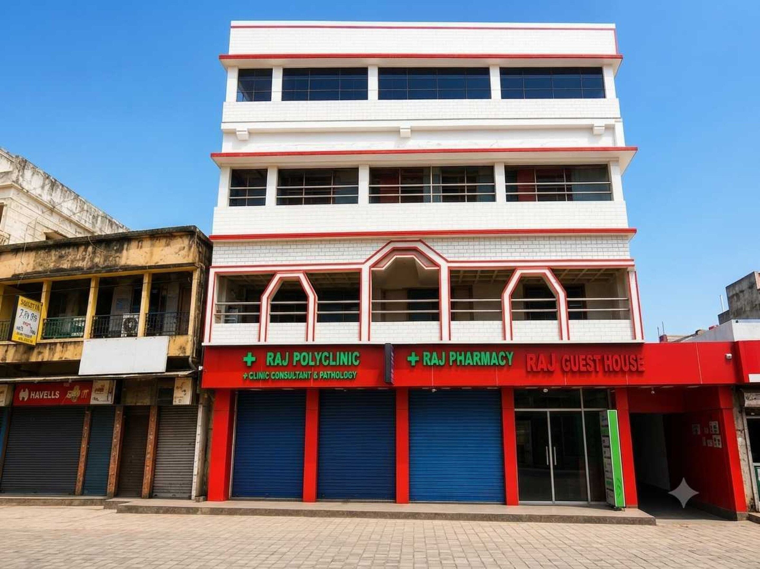 Un edificio de varios pisos con letreros que indican Raj Polyclinic, Raj Pharmacy y Raj Guest House.