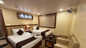 Een hotelkamer met twee bedden, een bank, een bijzettafeltje en een plafondventilator.