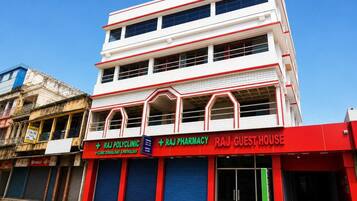 Un edificio de varios pisos con letreros que indican Raj Pharmacy y Raj Guest House.