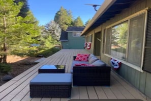 A covered outdoor deck with wicker furniture and a small shed in the background.