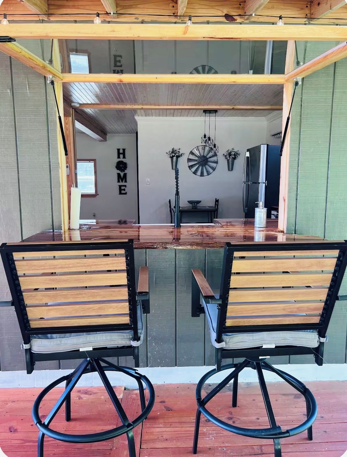Un coin repas avec une table en bois et deux chaises, une horloge et un réfrigérateur.