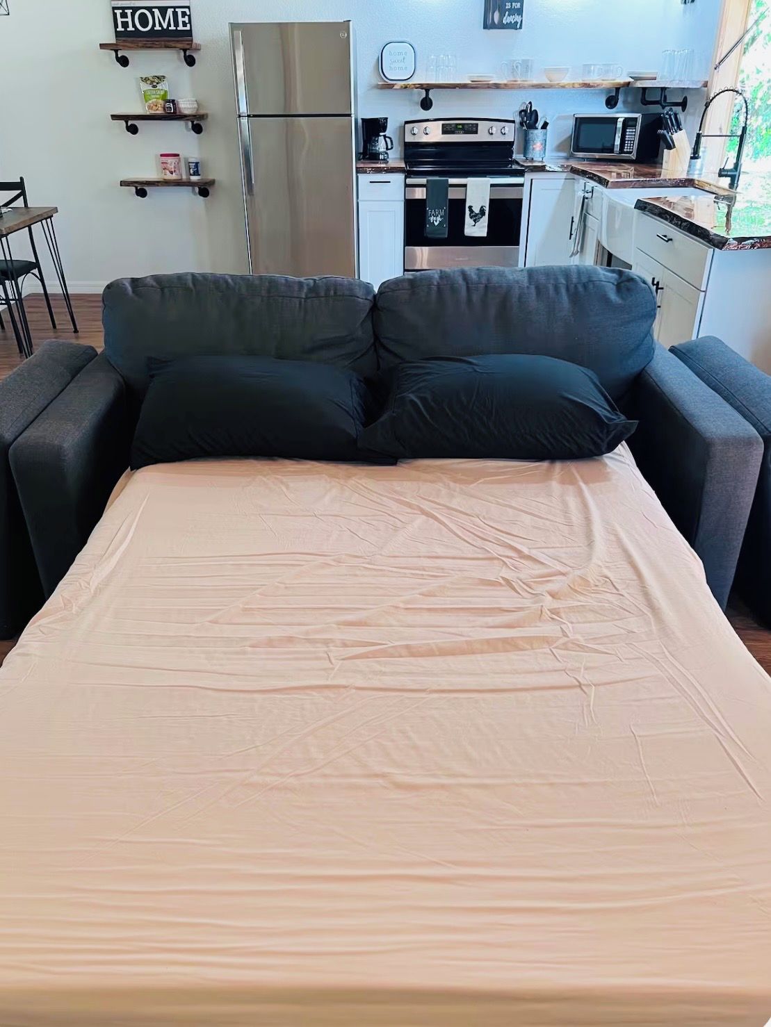 A room with a bed, a kitchenette, and a sofa.