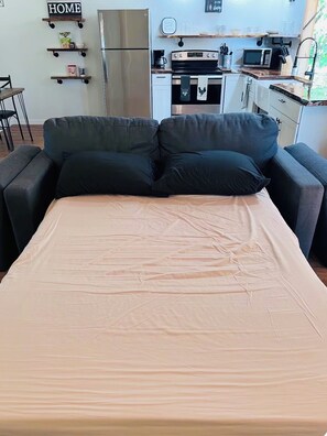 Une chambre avec un lit, un coin cuisine et un canapé.