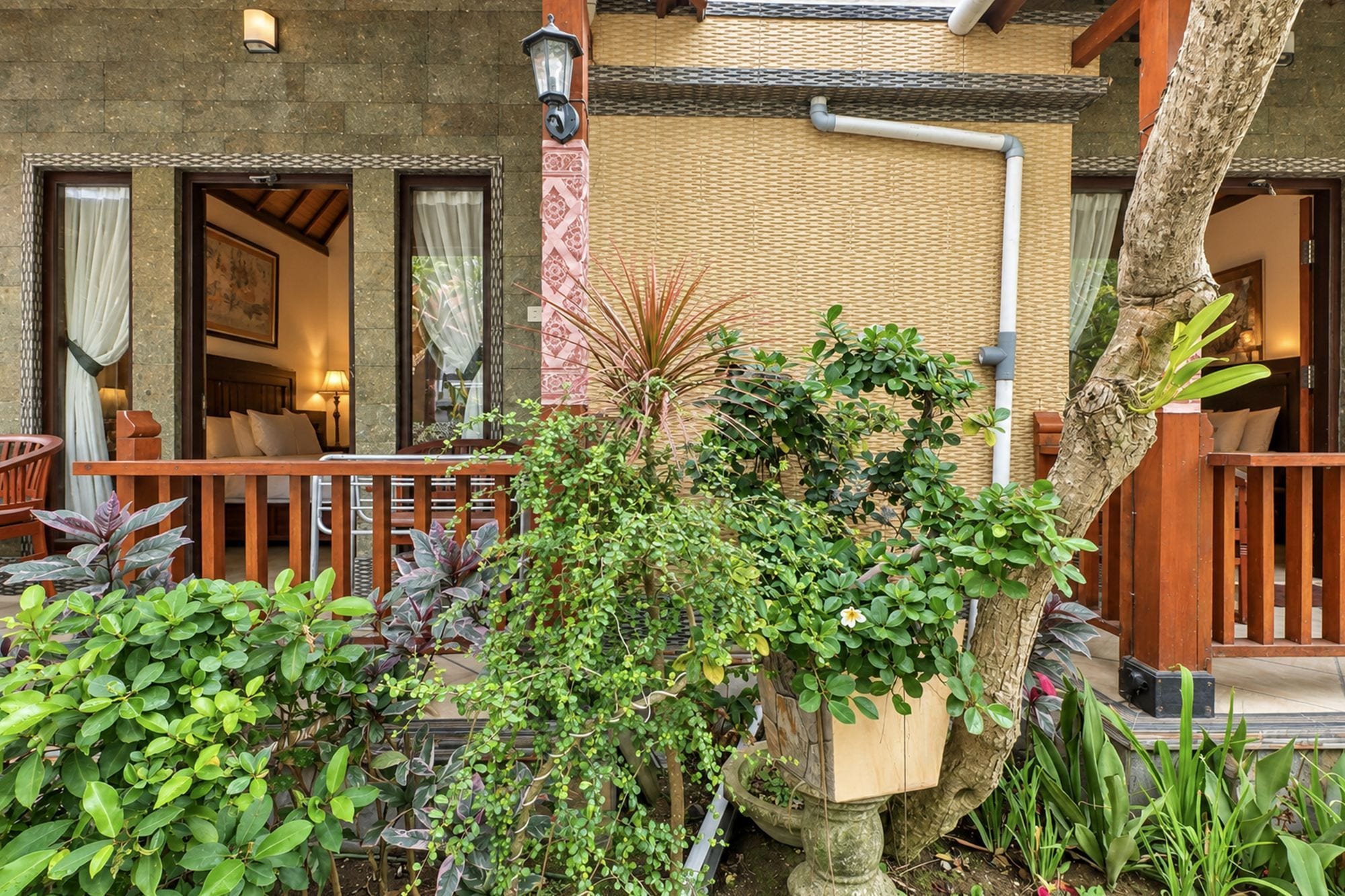 An outdoor area with a wooden deck, potted plants, and a stone wall.