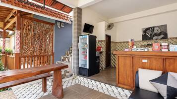 A reception area with a wooden desk, a refrigerator, and a seating area with a bench and a sofa.