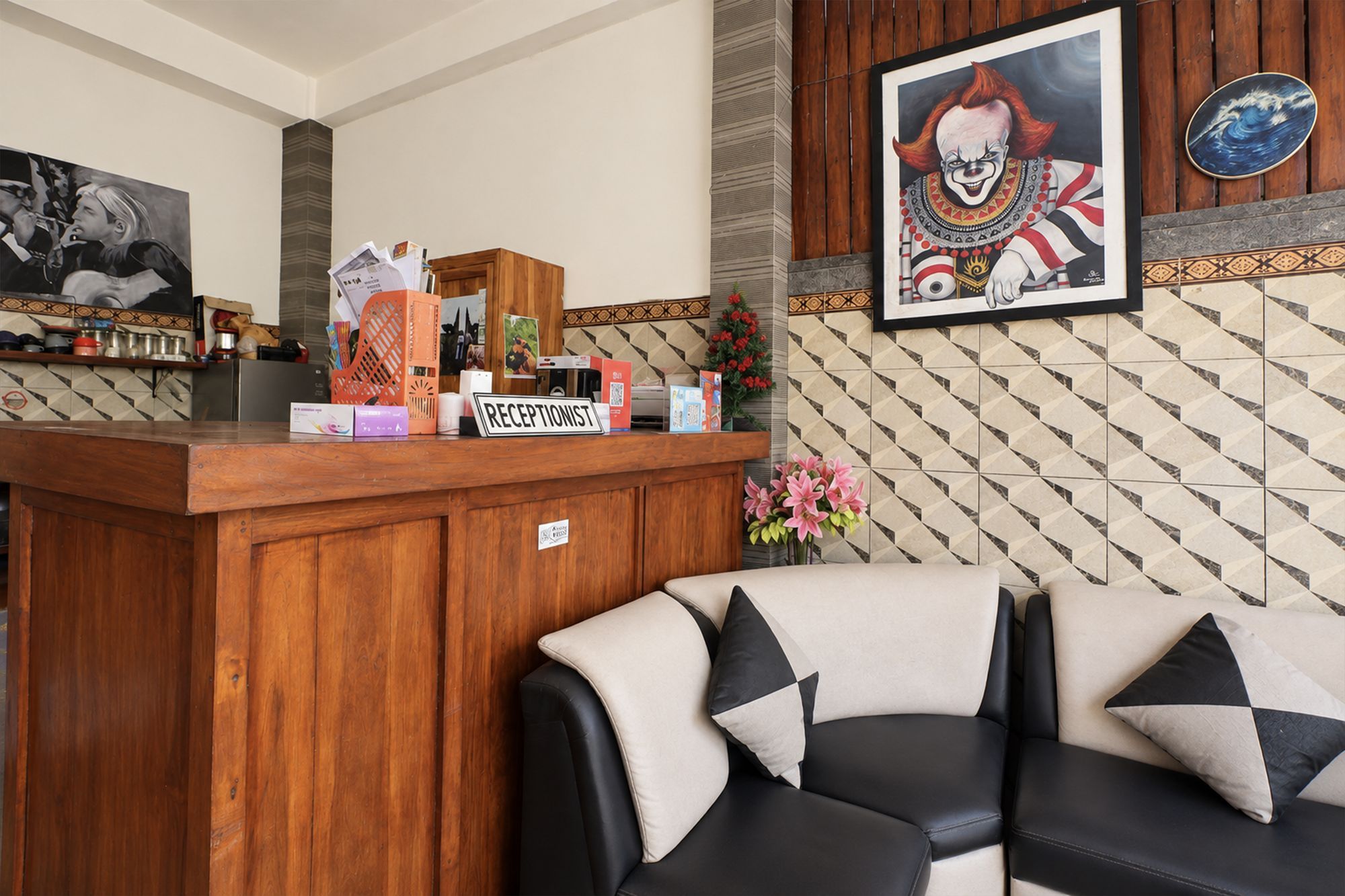 Una zona de recepción con un escritorio de madera, una obra de arte enmarcada y una pared de azulejos.