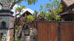 A gated entrance with a stone pathway leading to a traditional building with a tiled roof.