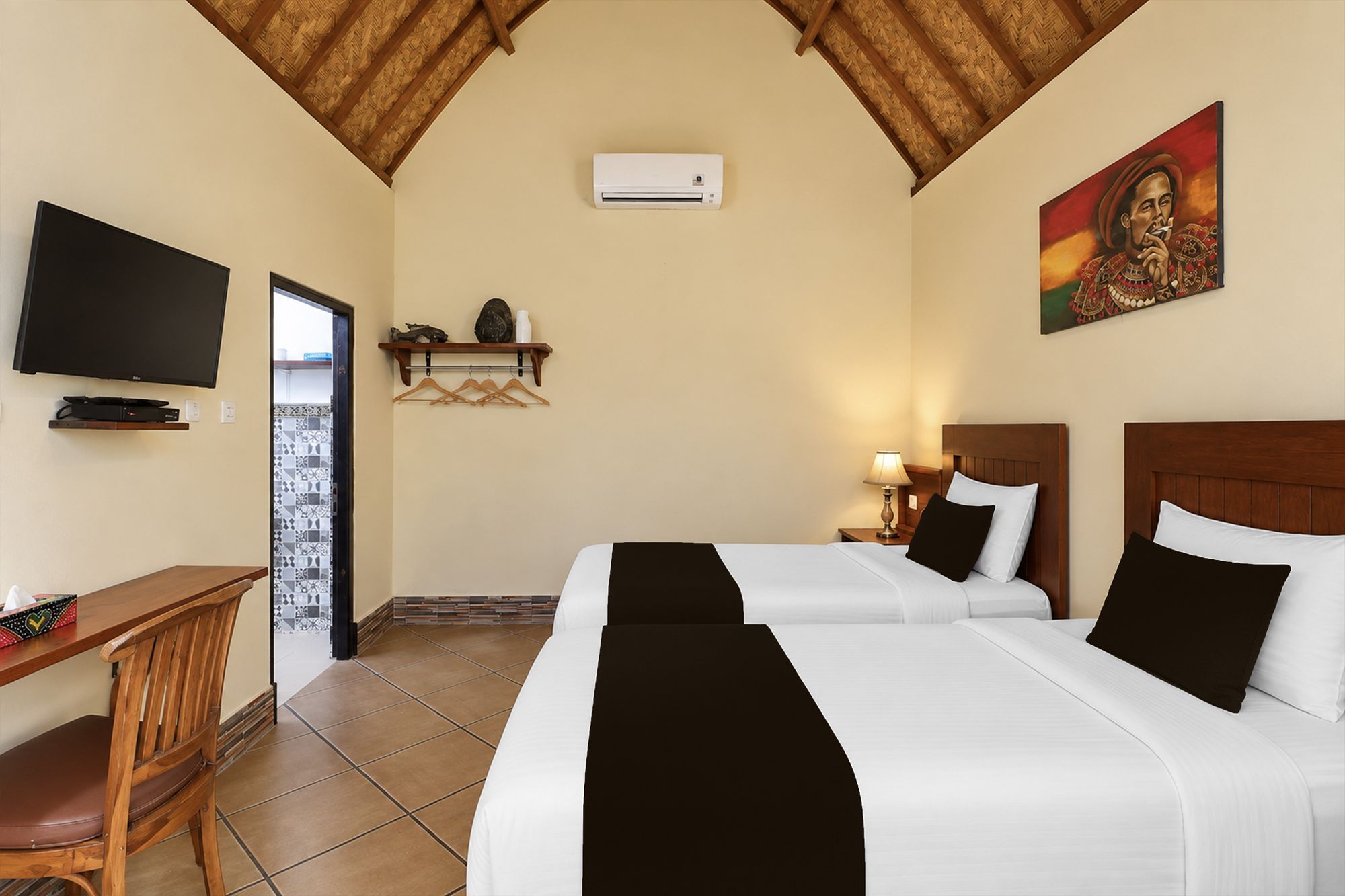 Habitación de hotel con dos camas, un televisor, un escritorio y un cuadro en la pared.