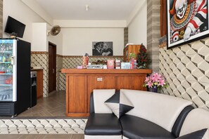 A reception area with a wooden counter, a sofa, a refrigerator, and a wall-mounted TV. - Belvilla The Cemok Cottage  (Penida Island)