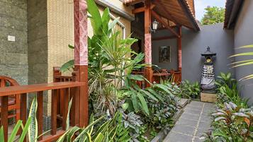 A courtyard with a wooden bench, potted plants, a stone pathway, and a traditional lantern.