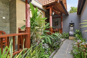 A courtyard with a wooden bench, potted plants, a stone pathway, and a traditional lantern. - Belvilla The Cemok Cottage  (Penida Island)