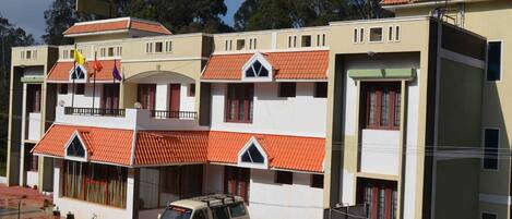 Un edificio de varios pisos con techo plano y un vehículo estacionado al frente.