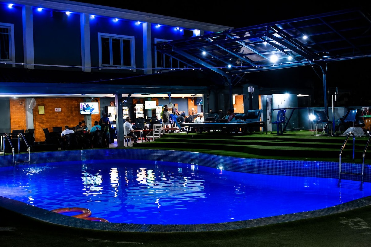 A swimming pool area with a covered seating area and a bar.