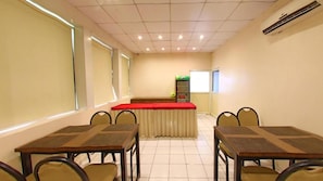 A conference room with a long table, chairs, a podium, and a whiteboard. - OYO Rooms Kanak Road (Rajkot)